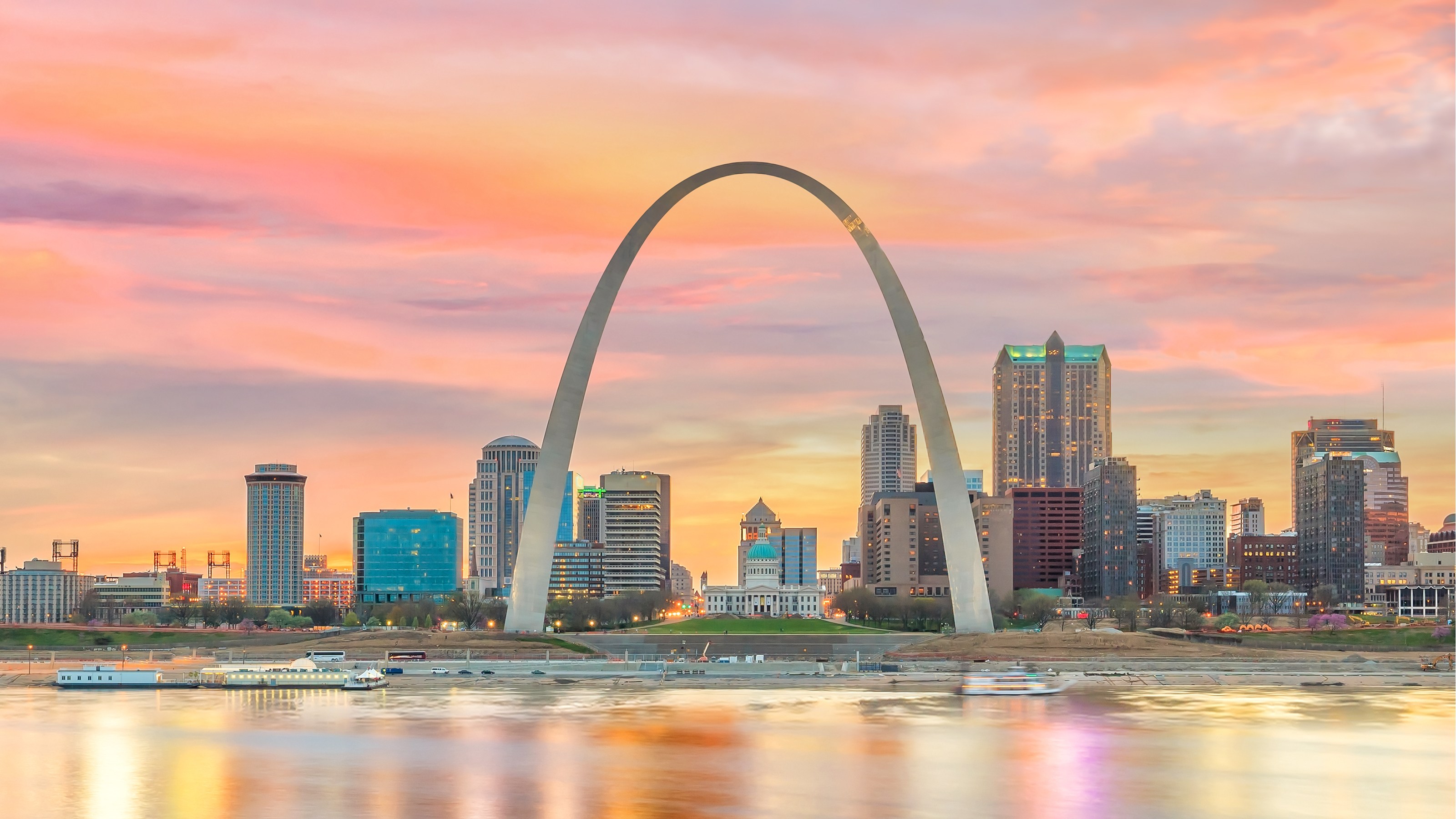 The Gateway Arch rising above the downtown St. Louis skyline and Mississippi riverfront at sunset